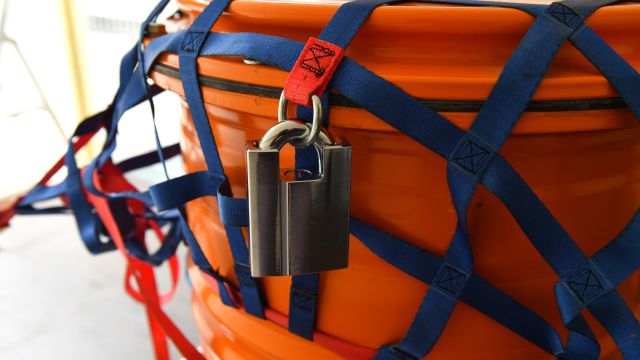 Oranges Abfallfass mit Gurten und Schloss gesichert Oranges Abfallfass mit Gurten und Schloss gesichert